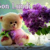 Un ours en peluche avec un bouquet de lilas décore la fenêtre, apportant une touche de douceur et de couleur pour commencer la semaine.