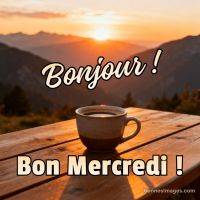 Tasse de café sur une table en bois au lever du soleil, montagnes en arrière-plan, texte « Bonjour ! Bon mercredi ! »